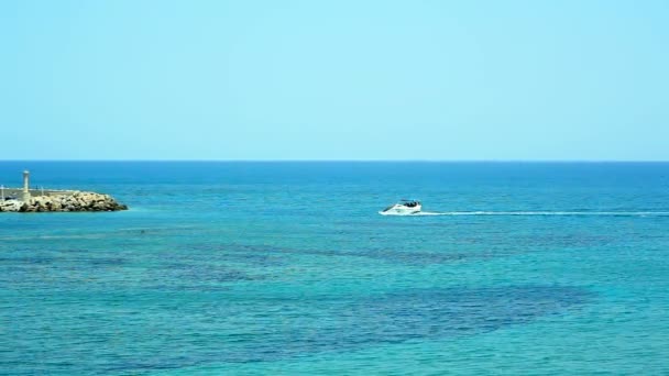 遊覧船は灯台のある美しい島に青い海に浮かびます。ギリシャの素晴らしい休日の概念. — ストック動画
