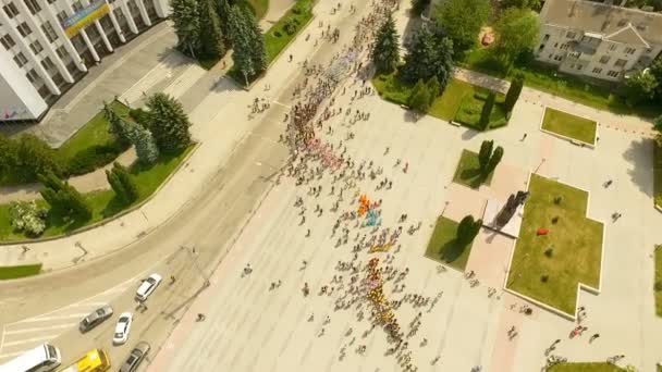 Vista aérea del solemne desfile de grupos de baile que marchan por las principales calles de la ciudad a lo largo del terraplén hasta el lago. Ucrania . — Vídeos de Stock