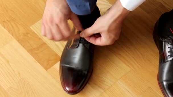 L'uomo lega i lacci delle scarpe sulle scarpe di pelle marrone, primo piano. Vista dall'alto . — Video Stock