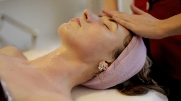 Feminino desfrutando de relaxante massagem facial no centro de spa cosmetologia . — Vídeo de Stock