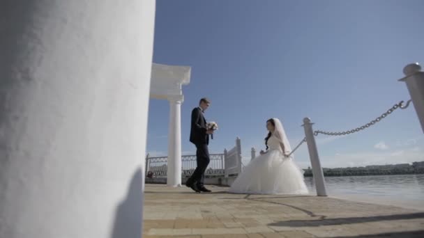 В день свадьбы. Невеста и жених танцуют у живописного голубого озера — стоковое видео