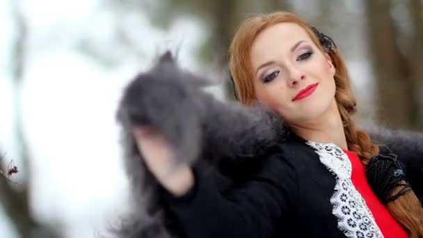 Красивая девушка кладет пушистую шаль на плечи на фоне зимнего леса — стоковое видео