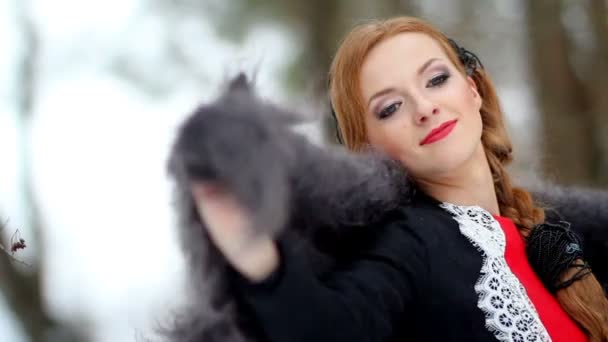 Beautiful girl puts downy shawl on shoulders on a background of a winter forest — Stock Video