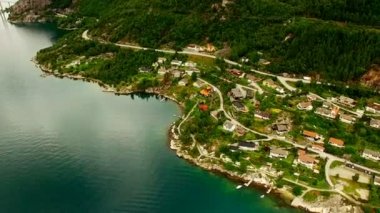 Bulutlu bir yaz gününde nehir kenarındaki resim gibi bir balıkçı köyü. Norveç. Hava görünümü.