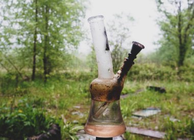 dirty glass bong on a background of gloomy nature clipart
