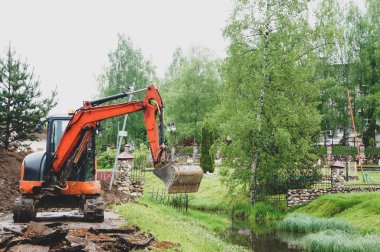 turuncu küçük kazıcı. Traktör kovasıyla asfalt kazın. Modern buldozer iş yerinde asfaltı ayırıyor