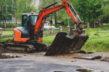 turuncu küçük kazıcı. Traktör kovasıyla asfalt kazın. Modern buldozer iş yerinde asfaltı ayırıyor