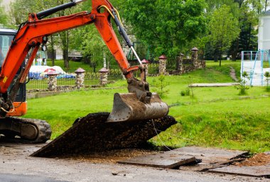turuncu küçük kazıcı. Traktör kovasıyla asfalt kazın. Modern buldozer iş yerinde asfaltı ayırıyor