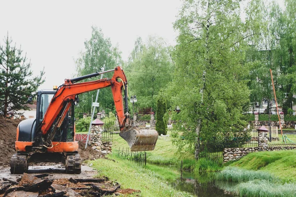 turuncu küçük kazıcı. Traktör kovasıyla asfalt kazın. Modern buldozer iş yerinde asfaltı ayırıyor