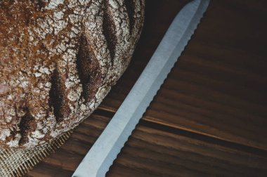 Taze pişmiş çavdar ekmeği, somun bıçağıyla ahşap bir masada, düz yatıyordu.