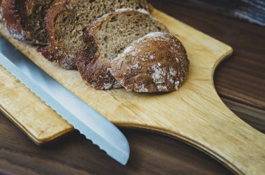 Tahtada dilimlenmiş çavdar ekmeği. Tahta bir masanın üzerinde ekmek için bir bıçakla