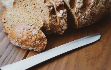 Dilimlenmiş çavdar ekmeği ekmek için bir bıçakla ahşap bir masada, köylü arka planında