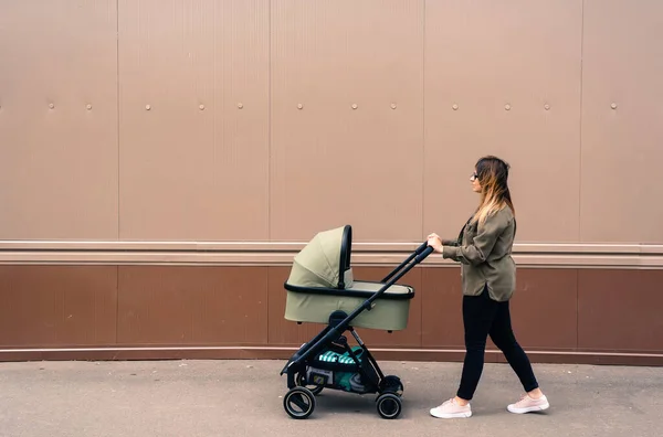 beautiful young mother walks with a stroller