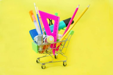 Sarı arka planda süpermarket tramvayında okul malzemeleri