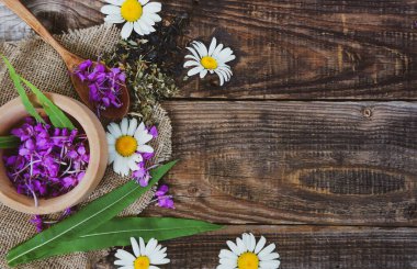 Tahta bir rustik masada çiçek ve papatya çayı, Epilobium angustifolium. Fireweed (Rosebay Willowhere), tahta kaşıkta pembe çiçekler, şifalı otlar, kopyalama alanı