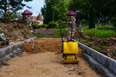Kumun üst katmanını eşit hale getiren, bir yol inşa eden, asfalta giden yolu hazırlayan bir manuel kaldırım..