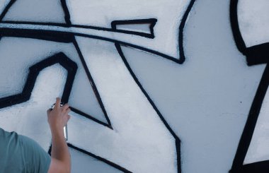 Sokak sanatçısı ortak bir duvara renkli graffiti çizer. Modern sanat konsepti, duvarına sprey boya sıkan el.