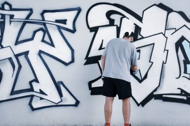Sokak sanatçısı ortak bir duvara renkli graffiti çizer. Modern sanat konsepti, duvarına sprey boya sıkan el.