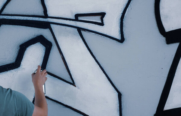 Street artist paints colorful graffiti on a common wall - Modern art concept, hand with a sprayer spray paint on the wall