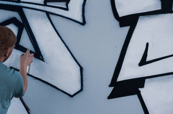 Street artist paints colorful graffiti on a common wall - Modern art concept, hand with a sprayer spray paint on the wall