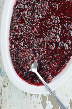 Eski ahşap masada ahududu reçeli porselen yemek takımında kaşık.