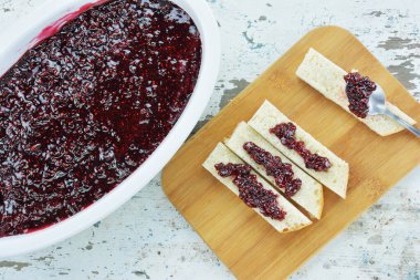 Ahududu reçelli porselen yemek takımı ve ahşap tahtada dilimler. 