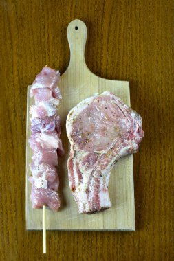 Çiğ souvlaki ve ahşap tahtada pişirilmeye hazır baharatlı domuz pirzolası.