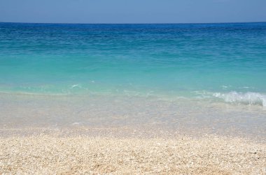 Arka plan olarak gökyüzü, deniz ve çakıl taşları