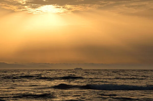 Bulutlu bir deniz manzarası ve dalgalı bir denizde seyahat eden bir gemi. 