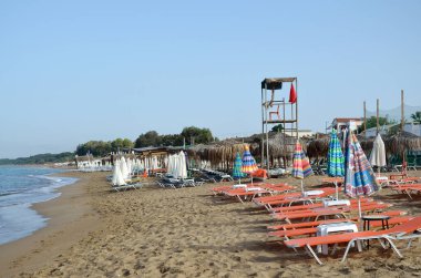 Güverte sandalyeleri ve güneşlik şemsiyeleri olan boş bir sahil.