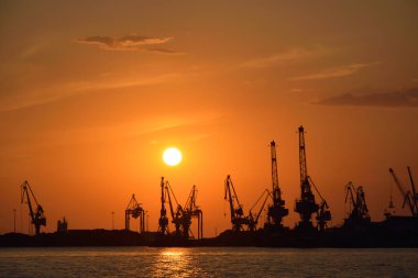 Gün batımında vinç siluetleri