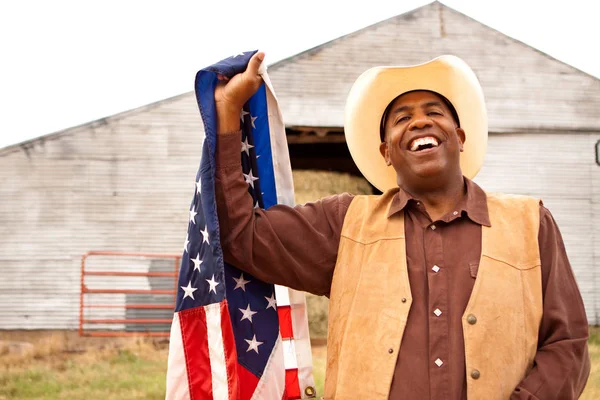 Cow-boy afro-américain tenant un drapeau américain . — Photo