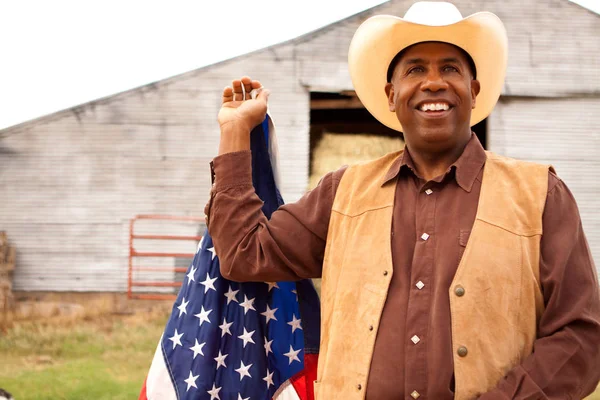 Cow-boy afro-américain tenant un drapeau américain . — Photo