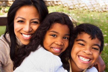 Biracial aile gülüyor ve dışarıda gülümseyen.