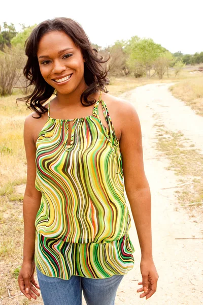 Mujer feliz sentada en un campo sonriendo . — Foto de Stock