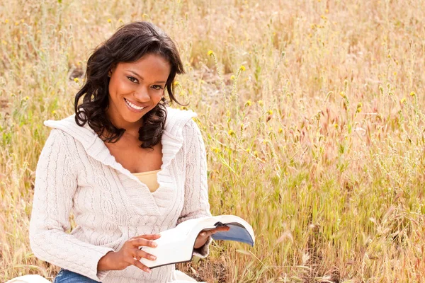 Lykkelig kvinne som sitter utenfor og leser . – stockfoto