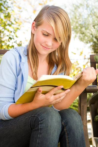 Young teen girl outside reading.