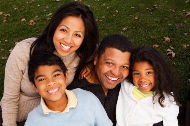 Biracial aile gülüyor ve dışarıda gülümseyen.