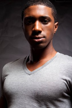 Ciddi görünümlü adam karanlık bir arka plan karşı ayakta.