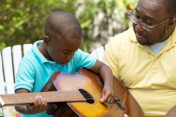 Padre teaaching su su hijo a tocar la guitarra . — Foto de Stock