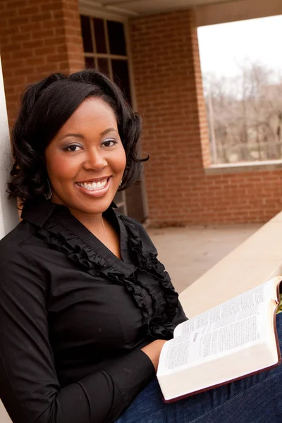 African American woman sitting outside reading.