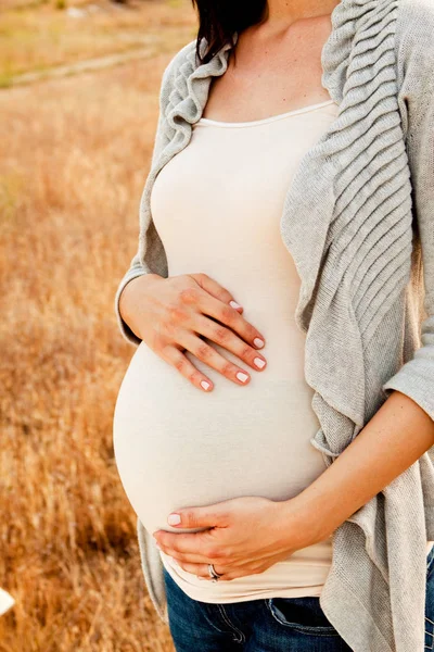 Těhotná žena ouside drží její břicho. — Stock fotografie