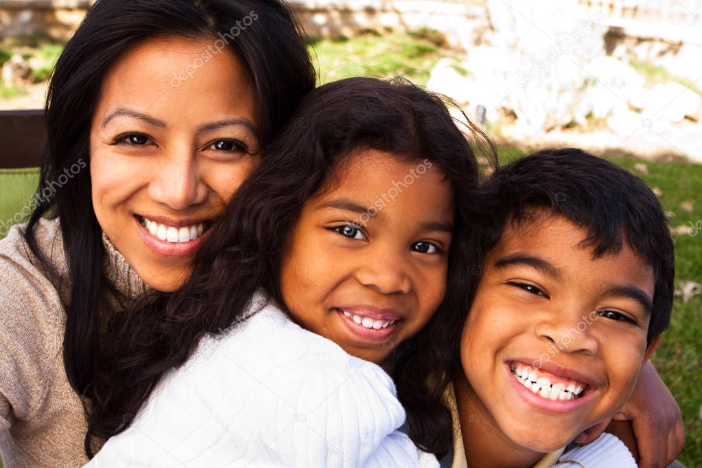 Biracial mother and her children laughing and smiling outside.