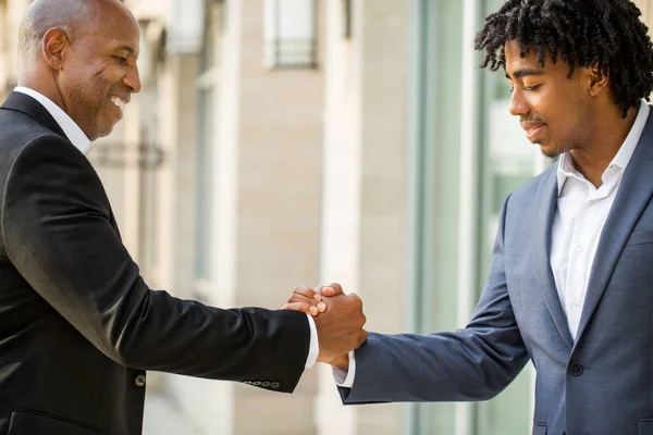 Reifen afrikanisch-amerikanischen lässig gekleideten Geschäftsmann beim Händeschütteln. — Stockfoto