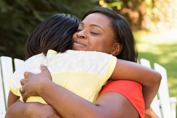 .Hugghing van de Afro-Amerikaanse moeder haar dochter buiten. — Stockfoto