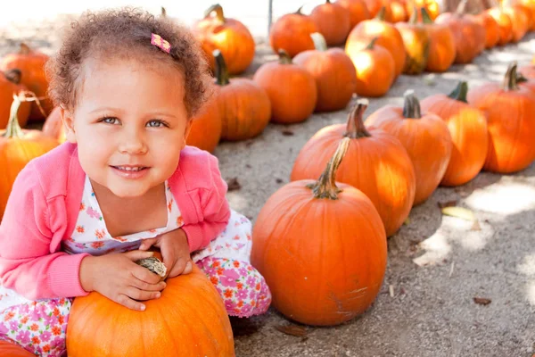 Küçük kız bir pumpking yama gülen. — Stok fotoğraf