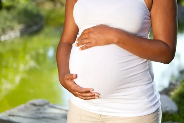 Joven mujer embarazada afroamericana sosteniendo su estómago . — Foto de Stock