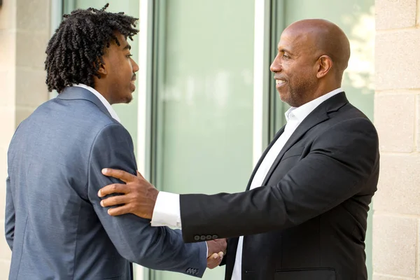 Reifen afrikanisch-amerikanischen lässig gekleideten Geschäftsmann beim Händeschütteln. — Stockfoto