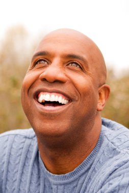 Mature African American man smiling sitting outside. clipart