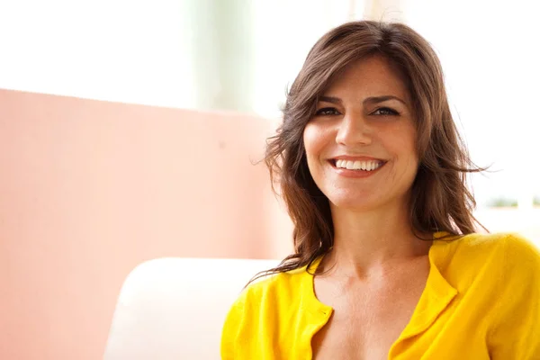 Mujer feliz sonriendo sentada en un sofá . — Foto de Stock